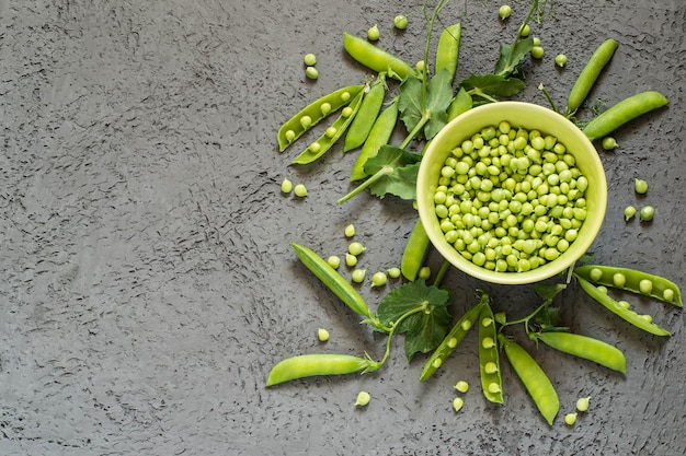 Green peas in bowl and on branches in pods