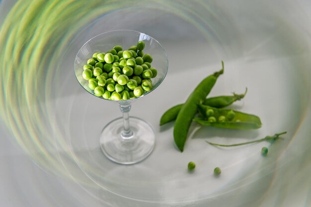 Green peas in a glass on white wooden background Concept of healthy eating fresh vegetables