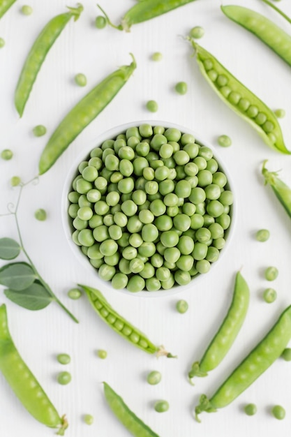 Photo green peas in white bowl on wooden background top view