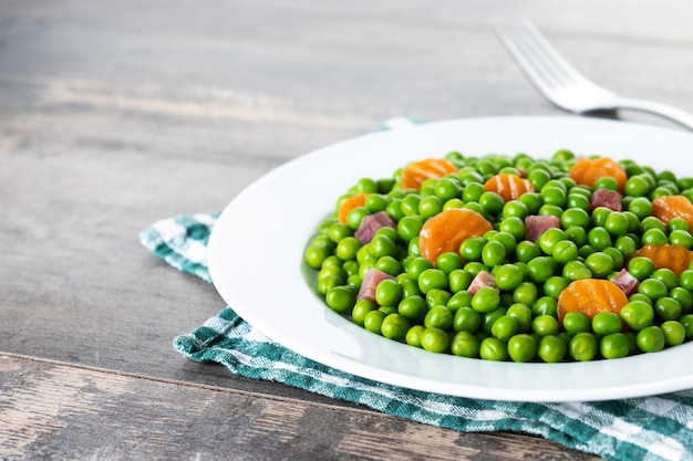 Photo green peas with serrano ham and carrot on wooden table