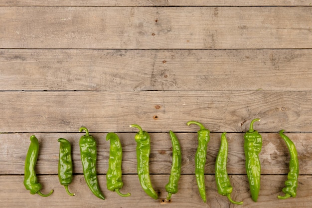 Green pepperoni peppers on the wooden table