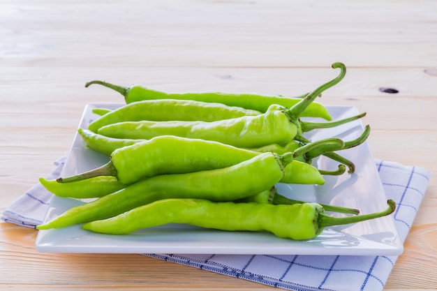 Green peppers on a plate and wooden floors.