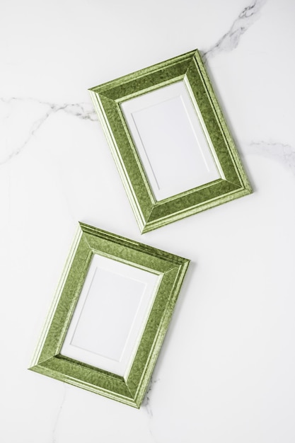 Green photo frame on marble flatlay