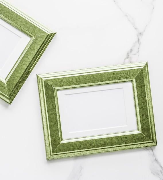 Green photo frame on marble flatlay