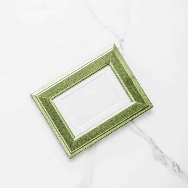 Green photo frame on marble flatlay