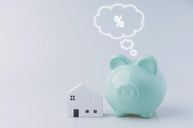 A green piggy bank for saving money uses investment property with a white little wood house on white background with copy space Save money financial concepts