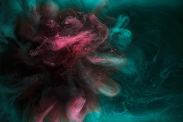 Green pink smoke on black ink background colorful fog abstract swirling touch ocean sea acrylic paint pigment underwater