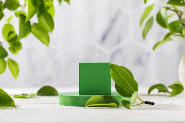 Green podium surrounded by young leaves for product presentation on a wooden background The organic concept