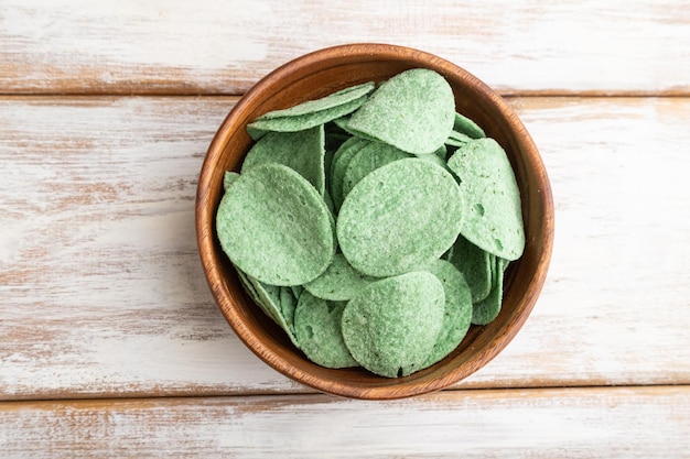 Green potato chips in wooden bowl on white wooden background Top view copy space