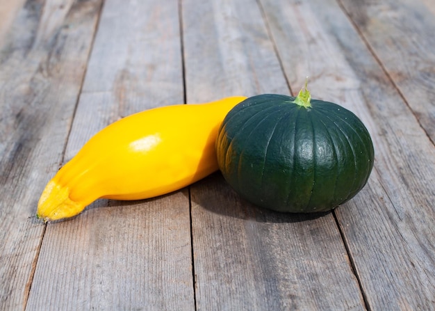 a green pumpkin and squash on a wooden table