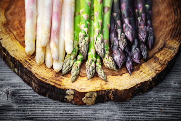 Green purple and white asparagus sprouts on wooden board closeup Top view flat lay Food photography