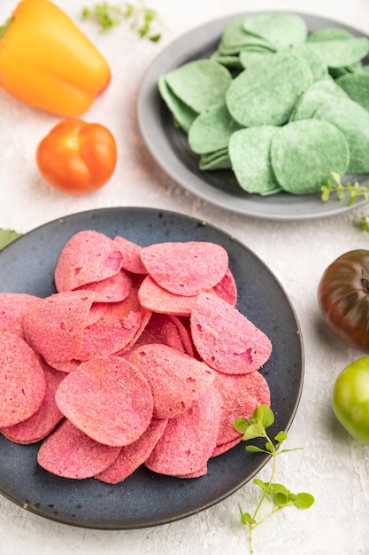 Green and red potato chips on gray concrete background Side view close up selective focus