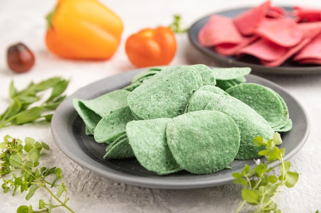 Green and red potato chips on gray concrete background Side view close up selective focus