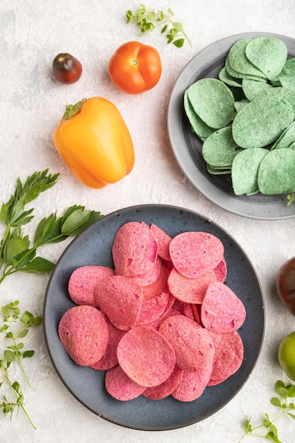 Green and red potato chips on gray concrete background Top view close up