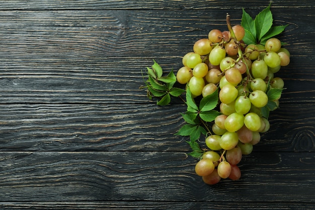 Green ripe grape on wooden background, space for text