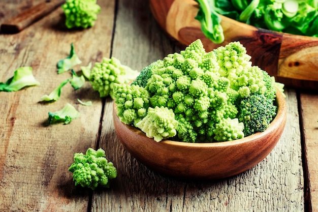 Green romanesco cauliflower in a wooden bowl vintage wooden background selective focus