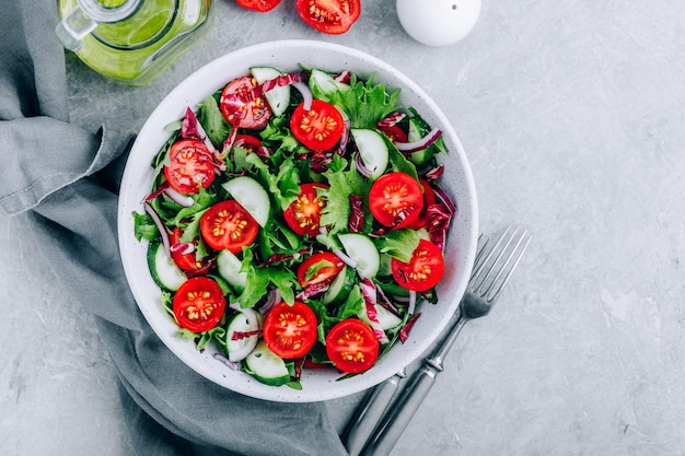 Green salad bowl with tomatoes cucumbers red onions radicchio and fresh lettuce Healthy eating Top view with copy space