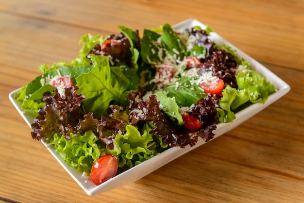 Green salad in white bowl on wooden table