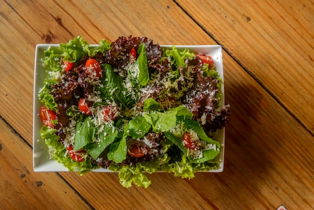 Green salad in white bowl on wooden table