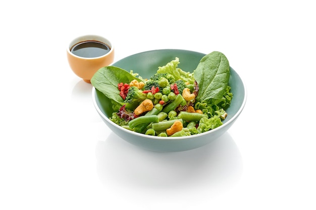 Green salad with asparagus broccoli and walnuts in a bowl on a white background