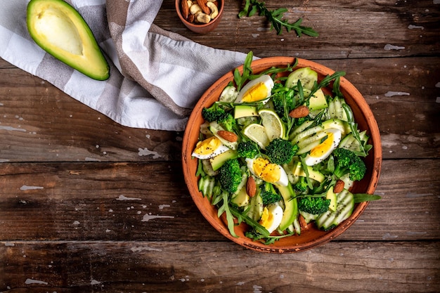 Photo green salad with avocado cucumber broccoli and egg healthy organic vegan salat with sliced avocado pear top view copy space