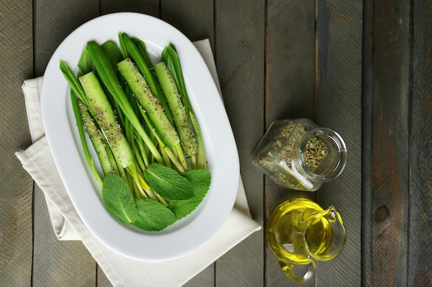 Green salad with cucumber and wild leek on wooden background