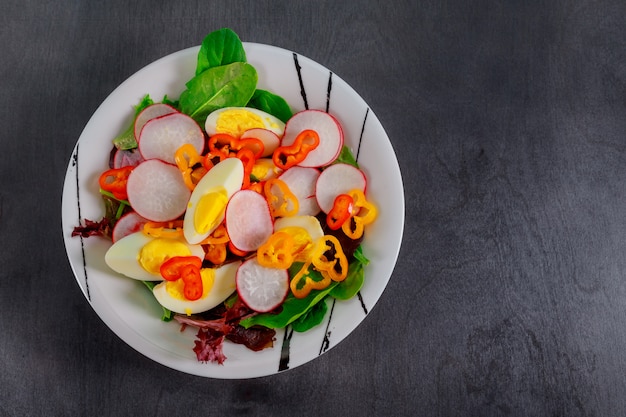 Green salad with eggs on wood background. Top view.