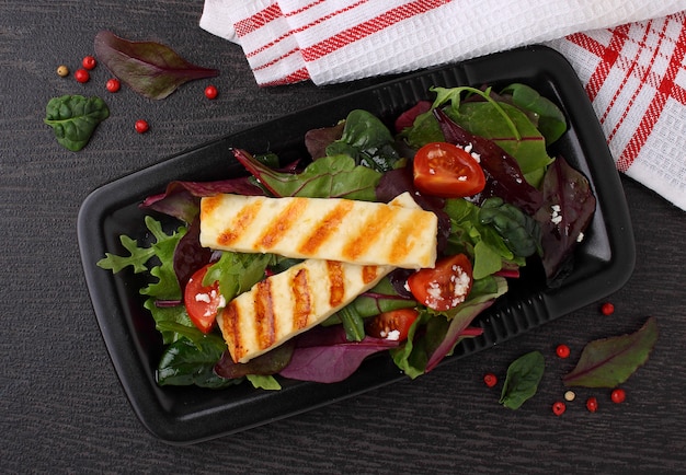 Green salad with fried halloumi cheese on a black plate