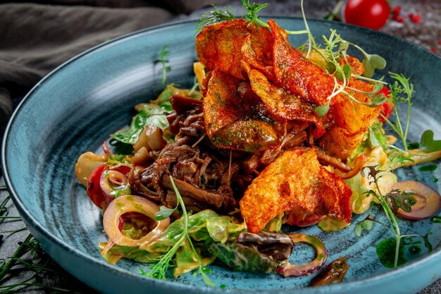 Green salad with fried potato chips tomatoes mushrooms and beef with red onion rings and arugula