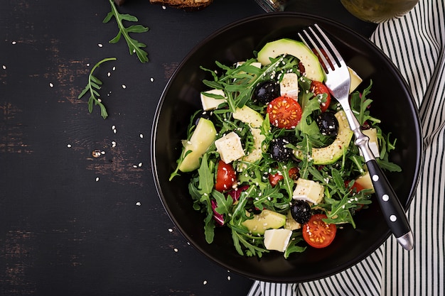 Green salad with sliced avocado, cherry tomatoes, black olives and cheese