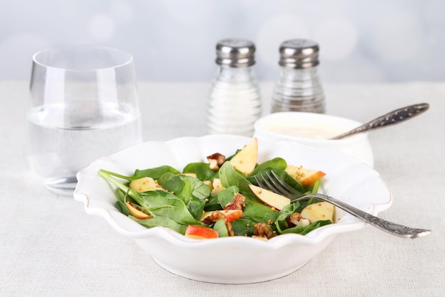 Green salad with spinach apples walnuts and cheese on light background