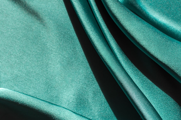 Green satin fabric pleats closeup Abstract trend background of the 2021 Tidewater Green color