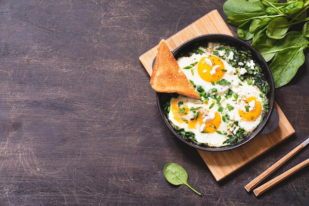 Green shakshuka in a cast iron skillet fried eggs with spinach and fried toast healthy breakfast