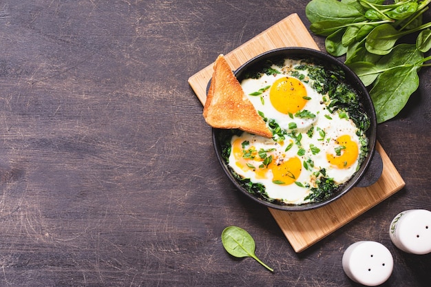 Green shakshuka in a cast iron skillet fried eggs with spinach and fried toast healthy nutritious breakfast