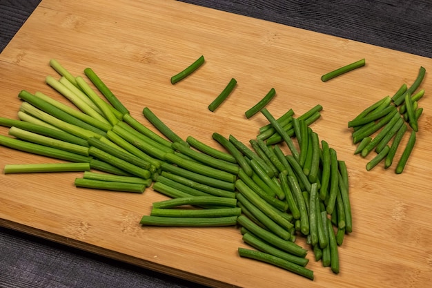 Green shoots of garlic or garlic spears on a cutting board prepared for cutting as part of the process of making garlic paste or for subsequent freezing