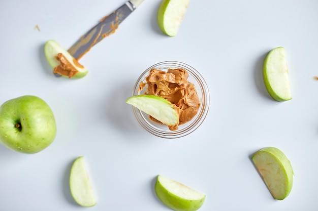 Green slices apples with peanut butter on white background healthy snack