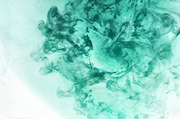 Green smoke on white ink background colorful fog abstract swirling emerald ocean sea acrylic paint pigment underwater