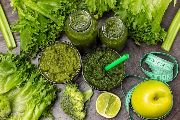 Green smoothie in glasses and bottles Measuring tape around an apple