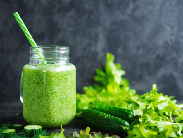 Green smoothie with cucumber, cabbage and healthy greens on the table