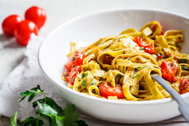 Green spinach pasta with tomatoes and herbs. Healthy vegan food concept.