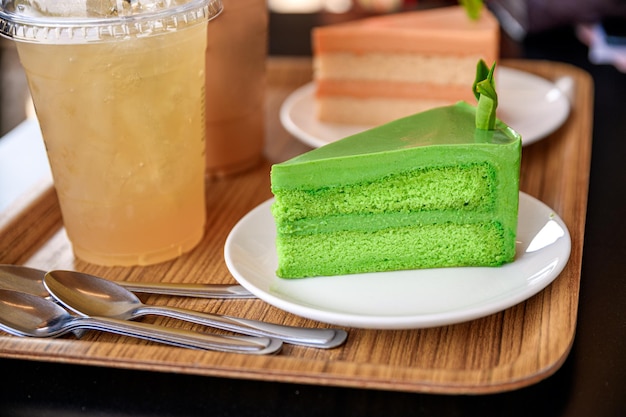 Green tea cheesecake with ice thai tea drink on table