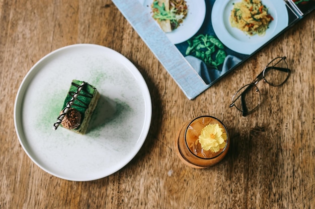 Green tea sliced cake dessert on white plate with summer mocktail in cafe table