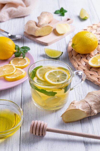 Green tea with lemon ginger and honey in a glass cup with oranges around on wooden table