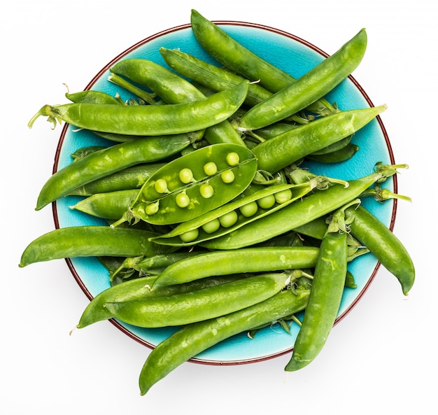 Green, tender, fresh and raw peas. In precise bowl of blue color. Isolated