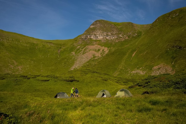 Green tent for the traveler sits on on a wide field, overlooking the evening time . camping getaway During long holidays for travelers