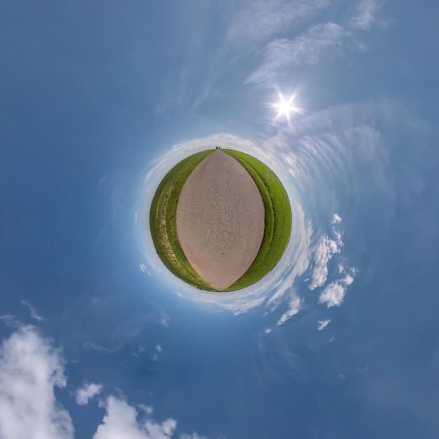 Green tiny planet in blue sky with sun and beautiful clouds Transformation of spherical panorama 360 degrees Spherical abstract aerial view Curvature of space