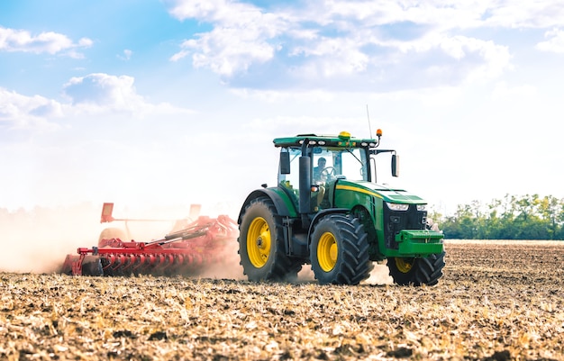 A green tractor is working in the field