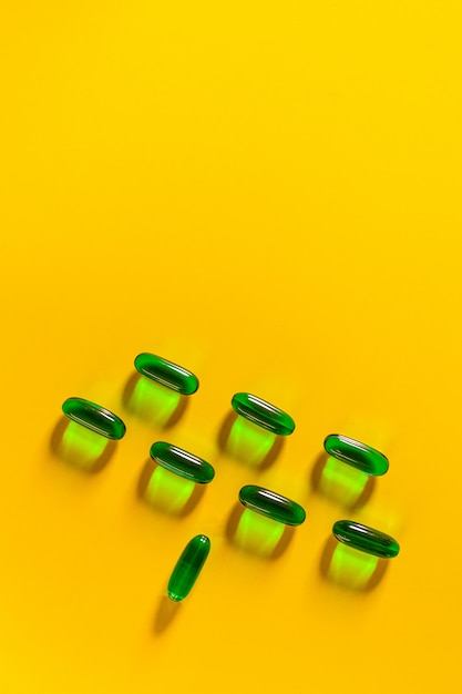 Green transparent capsules laid out on a yellow .Health . Healthy lifestyle . The concept of pharmacology. The concept of medicines. Medicine concept.