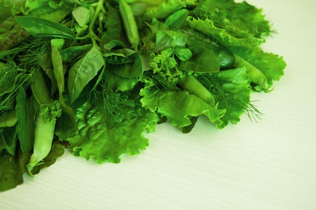 Green vegetable salad basil dill sorrel peas cucumber on the white background top view