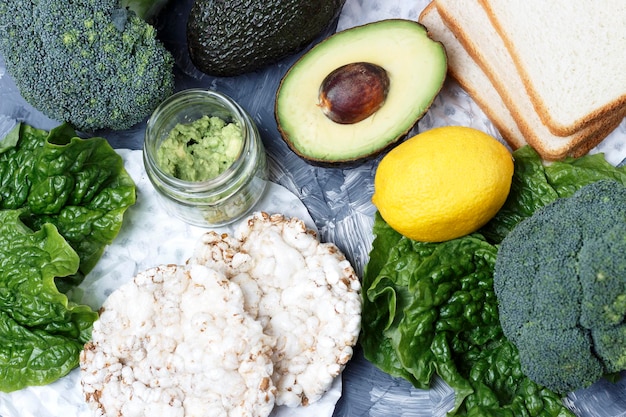 Green vegetables and bread on gray background top view healthy food concept